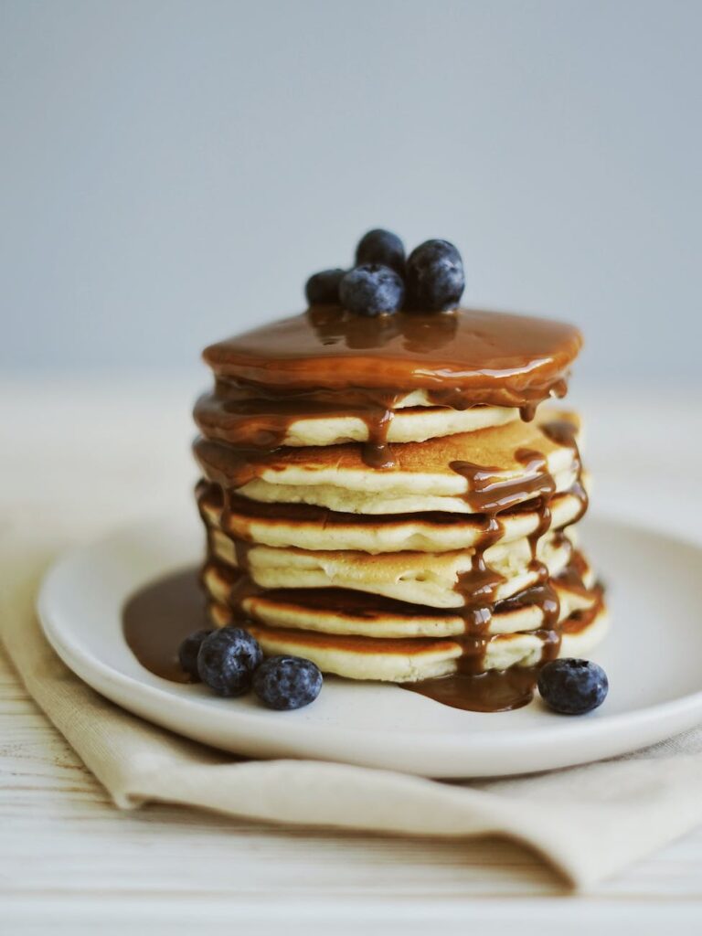 shallow focus photography of pancakes with blueberries and syrup